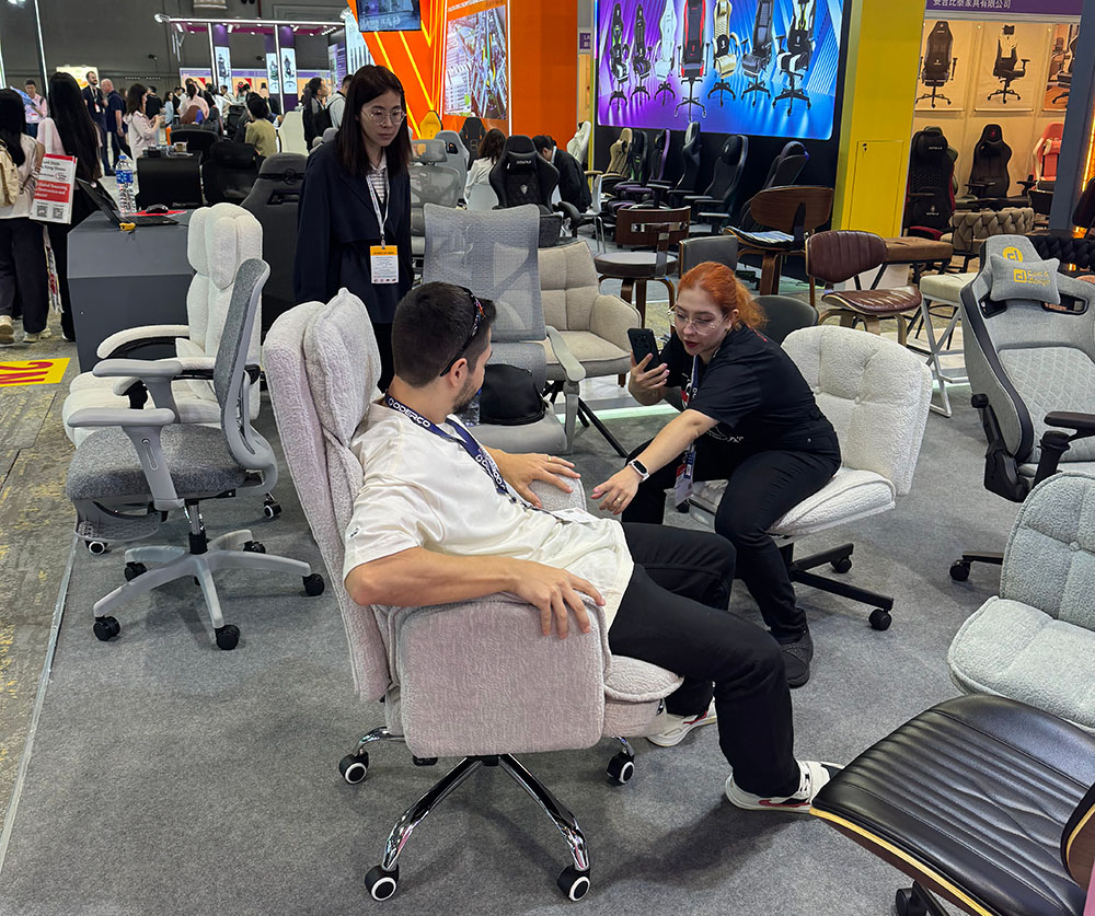 Visitors testing upholstered office chairs and accent chairs at Jindou Furniture booth during Global Sources Hong Kong Spring Exhibition